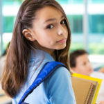 Elementary schoolgirl looking back while entering classroom